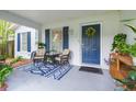 Inviting front porch with seating area and a blue patterned rug leading to the blue front door at 6412 S Richard Ave, Tampa, FL 33616