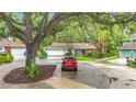 View of the home nestled among mature trees, with a driveway leading to the attached garage at 6901 Arbor Oaks Ct, Bradenton, FL 34209