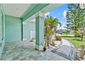 Covered front porch showcasing tiled flooring, supporting columns, and a beautifully landscaped yard at 716 Laurel Ave, Venice, FL 34285