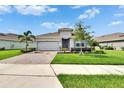 Well-maintained single-story home showcasing a brick driveway, green lawn, and mature landscaping at 11785 Little River Way, Parrish, FL 34219