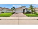 Beautiful one-story home boasts mature landscaping, a brick driveway, and an attached two-car garage at 11785 Little River Way, Parrish, FL 34219