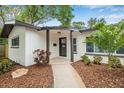 Charming covered entryway features a stylish front door, lush landscaping and a welcoming path at 1349 Tyrone N Blvd, St Petersburg, FL 33710