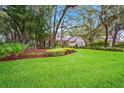 Single-story home with beautifully landscaped yard, featuring mature trees and green lawn at 17802 Mission Oak Dr, Lithia, FL 33547