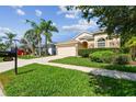 Inviting home with lush green lawn, mature palm trees, and a paved driveway at 2609 Rosehaven Dr, Wesley Chapel, FL 33544