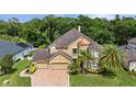 Aerial view of a beautiful two-story home showcasing a manicured lawn, mature trees, and a brick driveway at 3148 Watermark Dr, Wesley Chapel, FL 33544