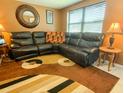 Inviting living room with a comfortable black leather sectional couch, and unique brown rug at 4214 Trucious Pl # 4212, New Port Richey, FL 34652