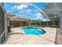 Screened-in pool area featuring a uniquely shaped pool, integrated spa, and brick paver patio at 5519 Reflections Blvd, Lutz, FL 33558