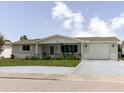 Lovely single-story home featuring a covered front porch, an attached garage, and lush greenery at 5840 Liddell Dr, New Port Richey, FL 34652