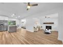Spacious living room featuring a white brick fireplace, wood floors, ceiling fans, and stainless steel refrigerator at 5927 10Th N St, St Petersburg, FL 33703