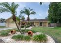 Charming single-story home with a well-manicured lawn, palm trees, and a two-car garage at 7902 Heather Ct, Tampa, FL 33634