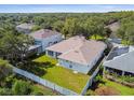 Aerial view of backyard with manicured lawn and white fence surrounded by lush trees at 10244 Shadow Branch Dr, Tampa, FL 33647