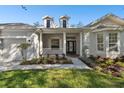 Inviting front porch with pillars and a landscaped garden leading to a stylish glass front door at 10244 Shadow Branch Dr, Tampa, FL 33647