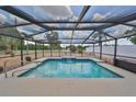 Screened-in pool area with waterfall feature, and a view of the lush backyard and surrounding landscape at 1224 W Del Webb Blvd, Sun City Center, FL 33573