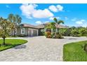 Beautiful home with a spacious driveway and tropical landscaping including palm trees, adding to the curb appeal at 15415 Mulholland Rd, Parrish, FL 34219