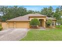 Inviting exterior with a three-car garage, beautiful landscaping, and a well-maintained lawn at 16608 Livingston Ave, Lutz, FL 33559