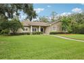 Inviting home showcasing a lush green lawn, mature trees, and a classic design with stone accents at 1803 143Rd E Ct, Bradenton, FL 34212