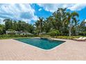 Inviting in-ground pool with a spa, surrounded by a spacious brick patio and lush tropical landscaping at 2395 Campbell Rd, Clearwater, FL 33765