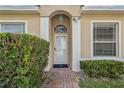 Inviting front entrance featuring a glass-paneled door, arched entryway, and manicured hedges at 2616 Tottenham Dr, New Port Richey, FL 34655
