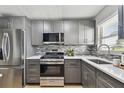 Modern kitchen featuring stainless steel appliances, gray cabinets, and a stylish backsplash at 2960 59Th S St # 303, Gulfport, FL 33707
