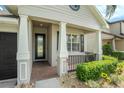 Close-up of the home's entry features a tiled porch, decorative columns, and manicured landscaping at 30753 Pumpkin Ridge Dr, Wesley Chapel, FL 33543