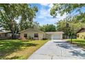 Single-story home with a manicured lawn and a concrete driveway leading to an attached one car garage at 39721 Meadowood Loop, Zephyrhills, FL 33542