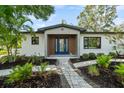 Stylish home entry with a blue double door, stone pathway, and lush landscaping at 454 35Th Ne Ave, St Petersburg, FL 33704