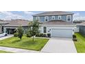 Two-story home features a light-blue facade, a two-car garage, and a well-manicured lawn at 8576 Broadstone Dr, Wesley Chapel, FL 33544