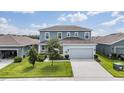 Two-story home features a light-blue facade, a two-car garage, and a well-manicured lawn at 8576 Broadstone Dr, Wesley Chapel, FL 33544