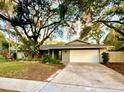 Inviting single-story home featuring a well-kept lawn, mature trees, and a neutral light gray exterior at 939 Woodland Dr, Palm Harbor, FL 34683