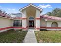 Exterior view of a home showcasing a covered front entrance with pillars and red-tiled roofing at 10446 Baylor Dr, Spring Hill, FL 34608