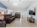 Spacious living room featuring tile flooring, a modern chandelier, and comfortable leather sofas at 10446 Baylor Dr, Spring Hill, FL 34608