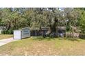 View of the home with mature trees and a portable storage container in the driveway at 12412 Lakeview Dr, Dade City, FL 33525