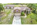 Front exterior featuring an attached garage, arched windows, and mature landscaping at 1332 Osceola Hollow Rd, Odessa, FL 33556
