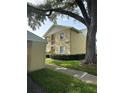 Charming condo building showcasing well-kept grounds, a sidewalk, a mature shade tree, and dedicated exterior storage at 1408 Millstream Ln # 206, Dunedin, FL 34698