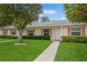 Inviting one-story home with lush green lawn and walkway leading to the front door with colorful window shutters at 1535 Nursery Rd # 110, Clearwater, FL 33756