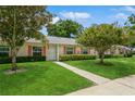 Charming one-story home with a manicured lawn, tidy landscaping, and a concrete path to the front door at 1535 Nursery Rd # 110, Clearwater, FL 33756