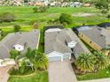 Aerial view of a well-maintained home with a screened pool, three-car garage, and lush green surroundings at 1723 Pacific Dunes Dr, Sun City Center, FL 33573