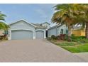 Charming home featuring a three-car garage, beautiful landscaping, and a brick driveway for added curb appeal at 1723 Pacific Dunes Dr, Sun City Center, FL 33573