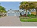 Charming home featuring a three-car garage, beautiful landscaping, and a brick driveway for added curb appeal at 1723 Pacific Dunes Dr, Sun City Center, FL 33573