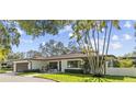 Inviting one-story home with well-manicured lawn, lush landscaping, and an attached two-car garage at 208 Live Oak Ln, Largo, FL 33770