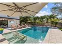 Outdoor pool area with lounge chairs, an umbrella, and a view of tropical landscaping at 208 Live Oak Ln, Largo, FL 33770