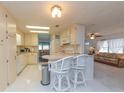 Bright kitchen with bar seating and white appliances, flowing into the living area at 3301 Alt 19 # 819, Palm Harbor, FL 34683