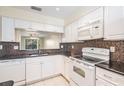 Bright kitchen features white cabinets, mosaic backsplash, and modern appliances, perfect for cooking enthusiasts at 340 Causeway Blvd # 105, Dunedin, FL 34698