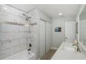 Bright bathroom featuring a shower-tub combo with white marble-like tiling, sleek vanity, and storage at 7547 Landmark Dr, Spring Hill, FL 34606
