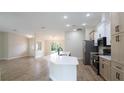 Modern kitchen with white cabinets, stainless steel appliances, and an open layout to the living area at 11483 Poorwill Ave, Brooksville, FL 34614