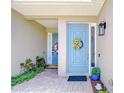 Double doorway entrance, featuring a colorful sunflower wreath on the main door and potted plants at 1411 Tessano Pl, Palm Harbor, FL 34683