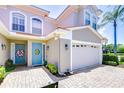 Home featuring a two-car garage, blue front door with a sunflower wreath, and a brick paved driveway at 1411 Tessano Pl, Palm Harbor, FL 34683