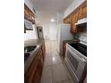 Galley kitchen with tile floor, white appliances, and brown cabinets opens to the living area at 226 Thorn Tree Pl # 226, Brandon, FL 33510