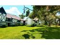 Striking view of Tudor-style condos surrounded by mature trees and a vibrant green lawn at 230 N Bayshore Blvd # 103, Clearwater, FL 33759
