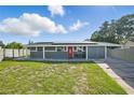 Inviting single-story home with gray exterior, red door, solar panels, and well-manicured front lawn at 2419 Wishing Well Way, Tampa, FL 33619